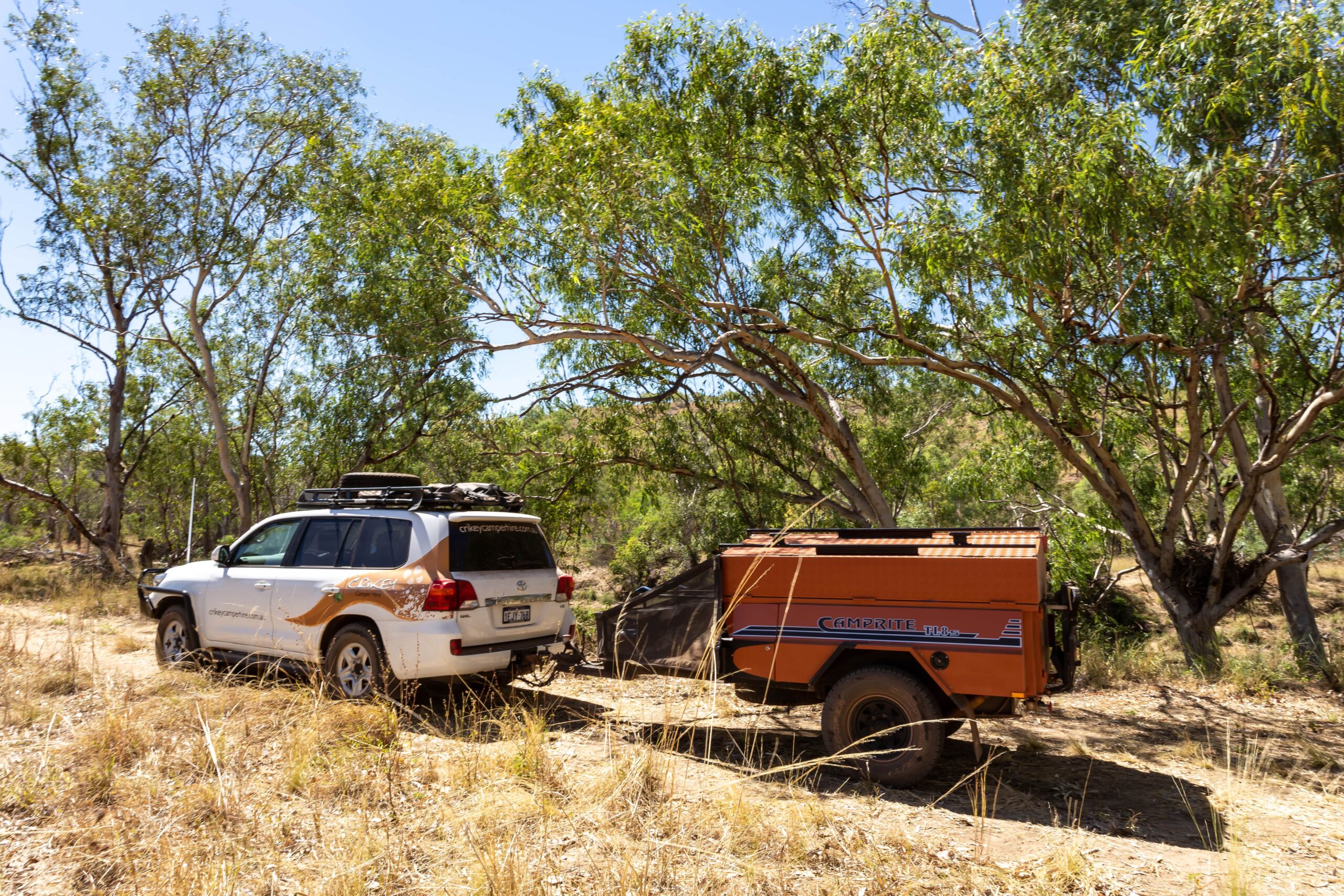 White 4wd towing a orange trailer in the outback